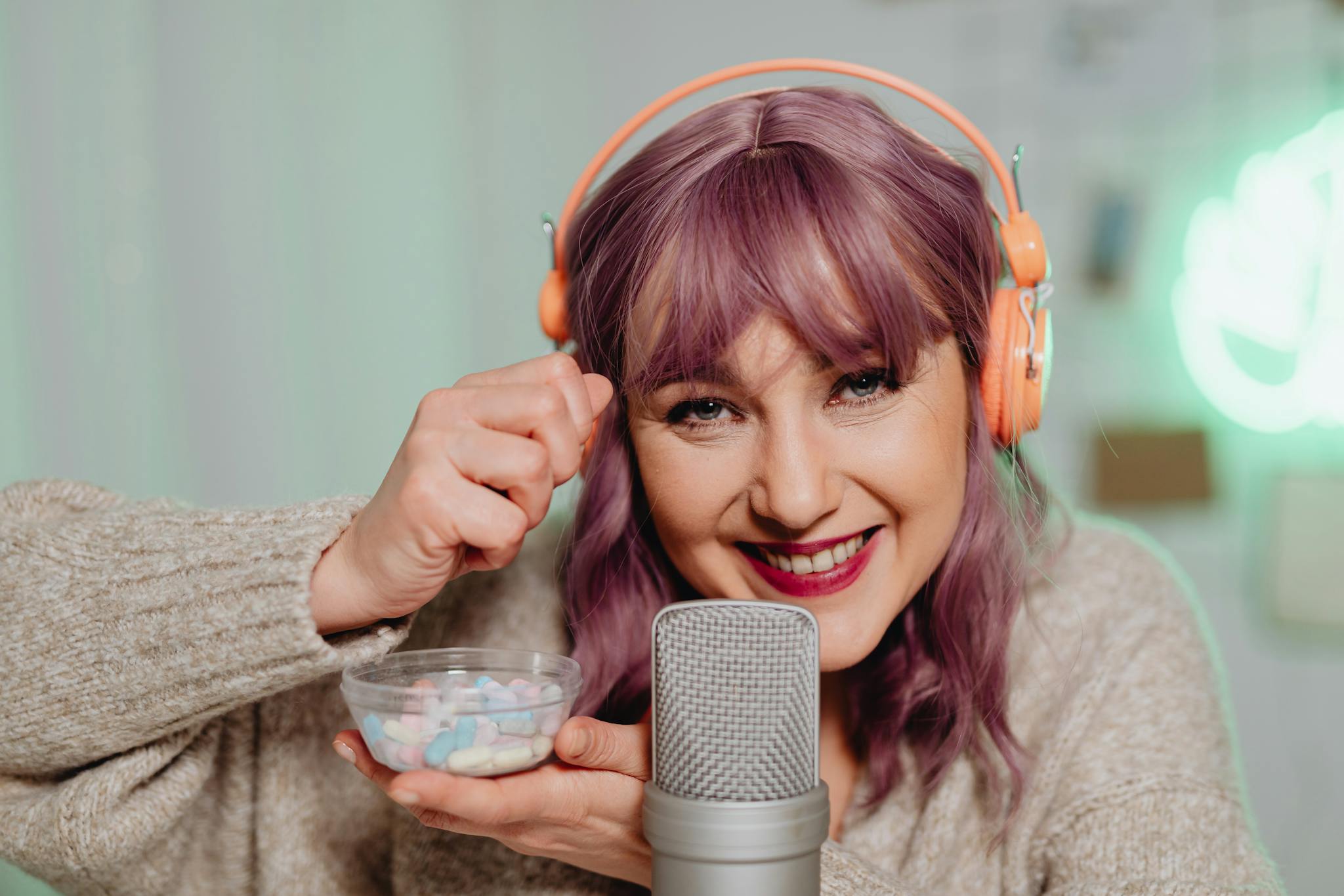 Woman with purple hair performing ASMR with candy and microphone indoors.